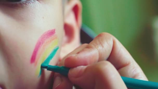 Vue rapprochée d'un petit garçon. parent LGBTQ peignant drapeau arc-en-ciel sur les joues. Journée de la fierté 2020, Famille LGBT, droits des femmes et concepts d "égalité
 - Séquence, vidéo