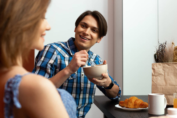 Happy man talking with woman during breakfast in kitchen - Фото, изображение