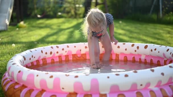 Küçük kız yazın arka bahçede şişme çocuk havuzunda oynuyor. - Video, Çekim