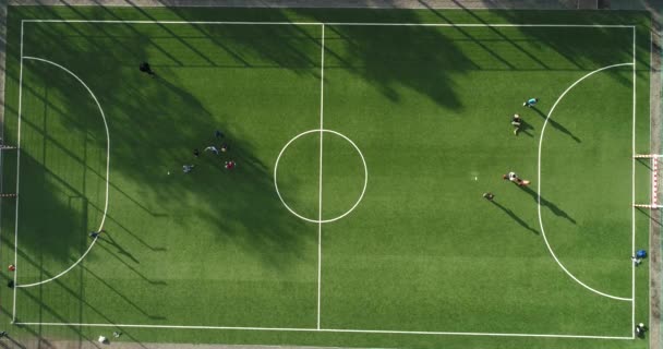 Luftaufnahme eines grünen Fußball- oder Fußballfeldes mit Jugendlichen, die an sonnigen Sommertagen Fußball spielen. - Filmmaterial, Video