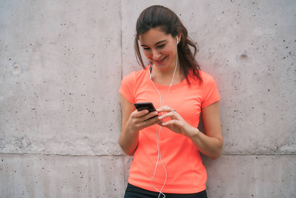 Portrait of an athletic woman using her mobile phone on a break from training. Sport and health lifestyle. - Foto, imagen