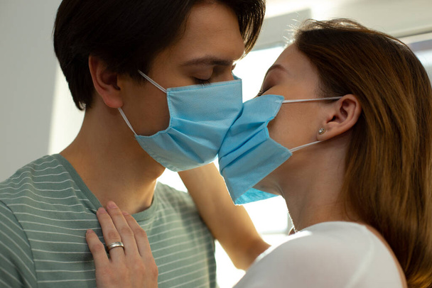 Romantikus csók két ember orvosi maszkban a világjárvány alatt - Fotó, kép