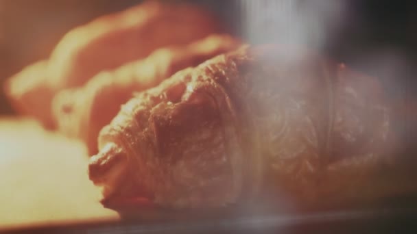 Az ízletes és friss croissant-ok a tálcán vannak a sütőben. - Felvétel, videó