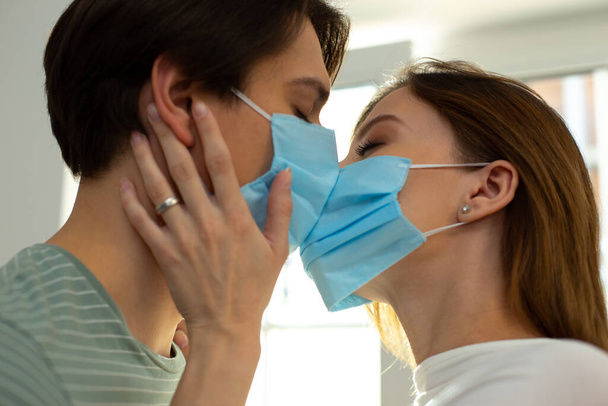 Romantic kiss of two loving people in medical masks - Foto, imagen
