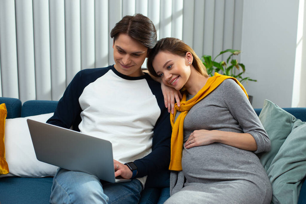 Peaceful young couple looking at the laptop screen and smiling - Foto, imagen
