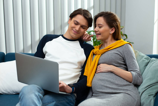 Excited pregnant woman doing online shopping with her husband - Foto, afbeelding