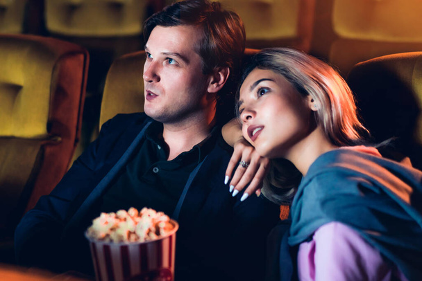 Caucasian lover enjoying to watch movie and eating popcorn together in the cinema - Fotó, kép