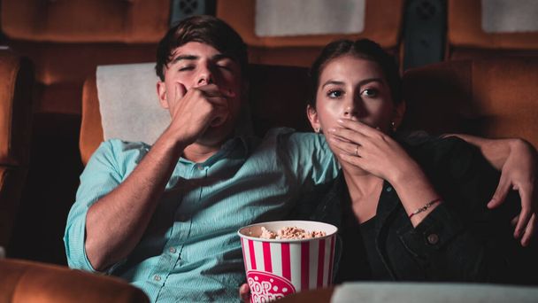 Loving paar man en vrouw kijken een saaie film en gapen op de bioscoop stoel - Foto, afbeelding
