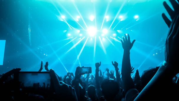 ナイトクラブDJパーティーコンサートで幸せな人々が踊り、ステージ上のDJから電子ダンスミュージックを聴く。Silhouette陽気な群衆は新年パーティー2020を祝います。人々のライフスタイル｜DJナイトライフ. - 写真・画像