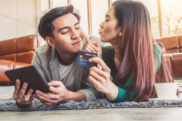Mladý pár používá kreditní kartu pro on-line nakupování na internetových stránkách doma. Číslo na kreditní kartě je vzorový. Na kreditní kartě nejsou uvedeny žádné osobní údaje. Online obchodní nákupní koncept. - Fotografie, Obrázek