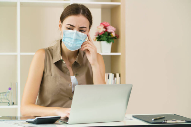 顔のマスクを身に着けている家で働く隔離された女性はコロナウイルスから保護する。コロナウイルス病の拡大を停止するための社会的距離の概念またはCOVID-19. - 写真・画像