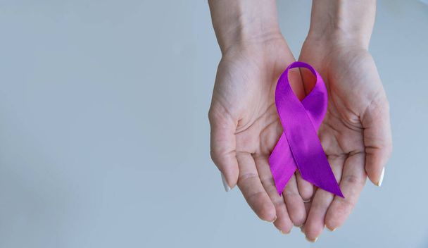 Alzheimer's Disease AD Awareness with purple ribbon clipping path on human helping hand for World Alzheimers day month concept. - Photo, Image