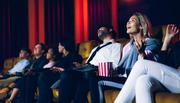 Группа зрителей счастливо и весело смотрит кино в кинотеатре. Концепция группового отдыха и развлечений. - Фото, изображение