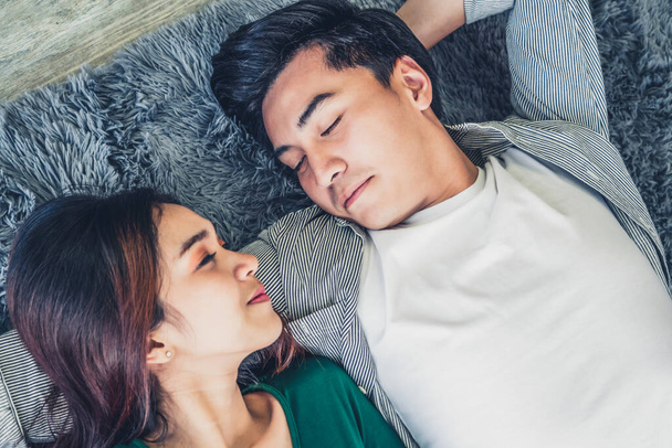 Ευτυχισμένο ζευγάρι Ασιατών ξαπλωμένοι στο χαλί στο πάτωμα του σαλονιού. Σχέση αγάπης και τρόπος ζωής έννοια. - Φωτογραφία, εικόνα