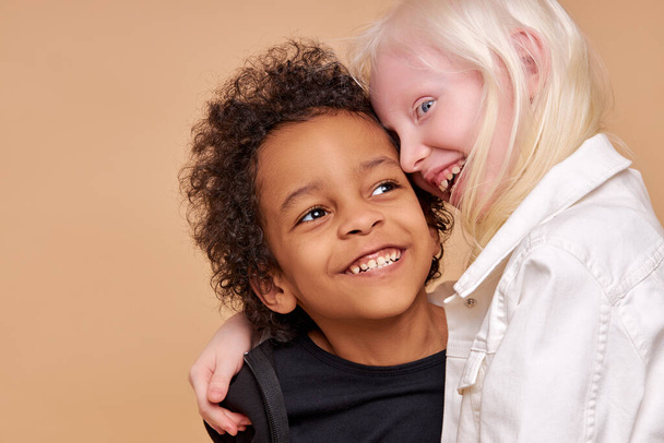 two friendly dark-skinned and albino children stand together - 写真・画像