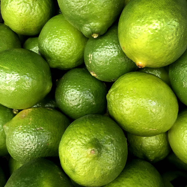Macro Photo of a ripe juicy lime fruit. Texture green citrus fruit lime. Background A lot of green sour lays lie on the store shelf. - Photo, Image
