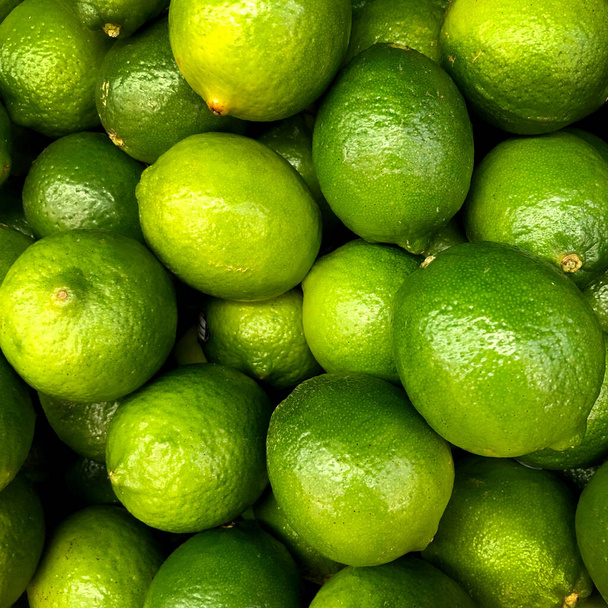 Makro foto zralého šťavnatého limetkového ovoce. Textura zelené citrusové plody vápno. Pozadí Na polici v obchodě leží spousta zelených kyselin. - Fotografie, Obrázek