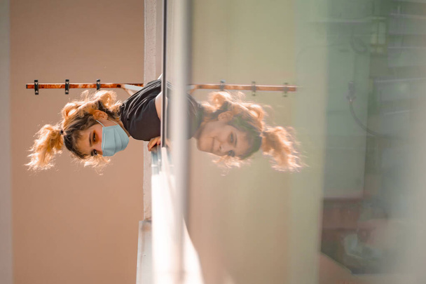 Blonde girl in window in quarantine reflected while corona virus pandemic - Photo, Image