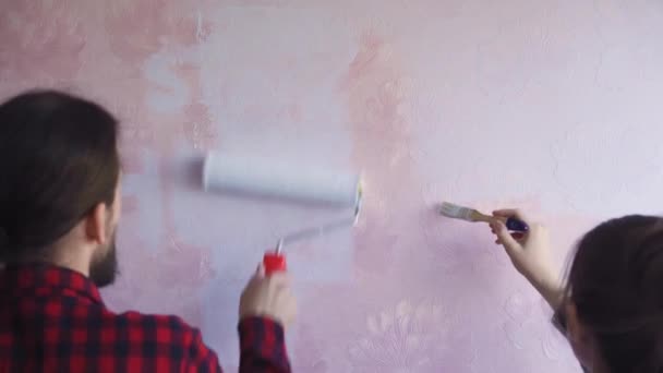 Gyönyörű pár Díszítik Az Új Lakás és Bolond Körül. Férj és feleség festik a falat görkorcsolyákkal, amiket világoskék festékbe mártottak. Ők boldogok és jó szórakozást. Felújítások otthon - Felvétel, videó