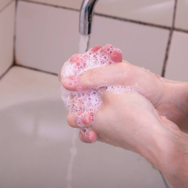 La mujer se lava las manos con jabón líquido, jabón suds, primer plano
 - Foto, imagen