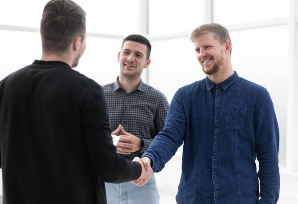 young men shaking hands in a creative office - Fotó, kép