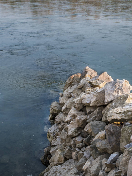 Stenen muur op het water, dient als bescherming. Grote stenen op elkaar gestapeld. - Foto, afbeelding