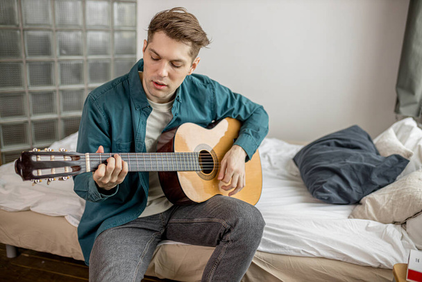 fiatal férfi gitározik otthon - Fotó, kép