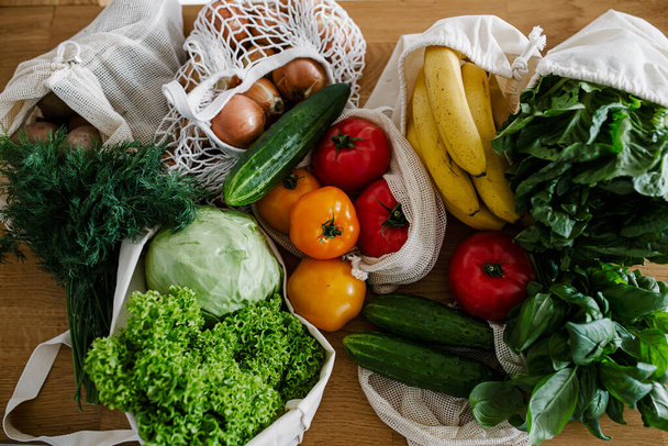 Verse groenten en fruit in eco katoen herbruikbare zakken op tafel in de keuken. zero waste shopping concept. Duurzaam leven - Foto, afbeelding