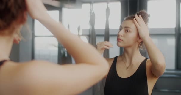 Attractive young cubinian woman straightens her hair infront of mirror wall of dance room before training, dancer in ballet studio, woman prepairs for workout, yoga and stretching, 4k 60p Prores 422 - Footage, Video