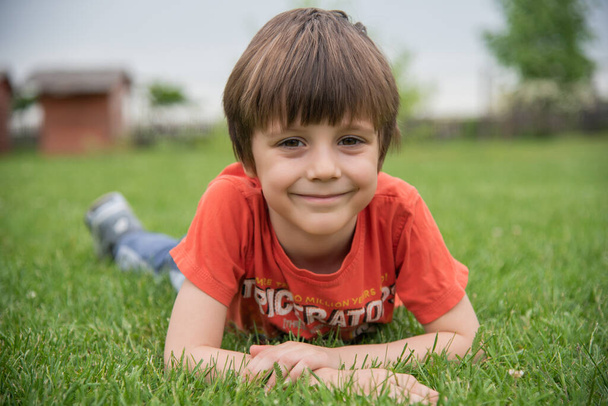 Słodki mały chłopiec leżący w trawie  - Zdjęcie, obraz