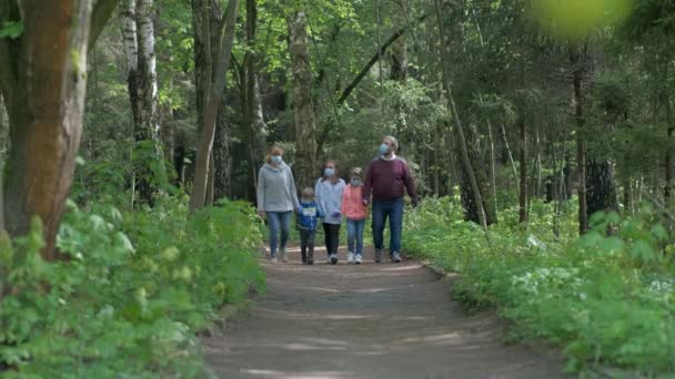 Family: father, mother, son and two daughters walk in the Park in medical masks in the spring. The concept of protection FROM covid-19 coronavirus infections. - Footage, Video