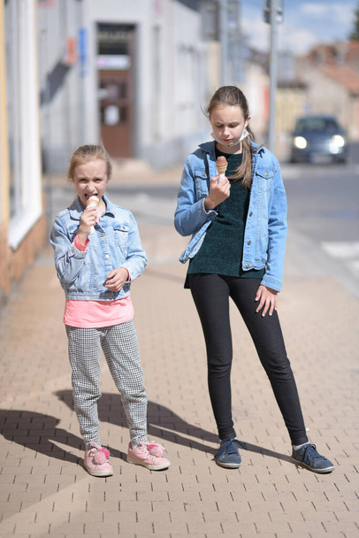 дві дівчини їдять морозиво на відкритому повітрі
 - Фото, зображення