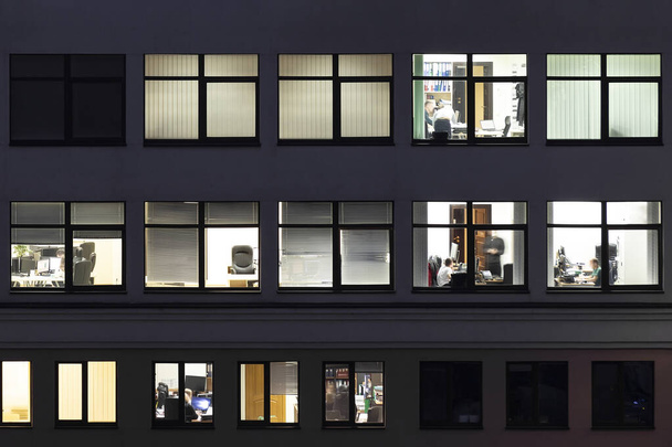 Vue aérienne nocturne de la façade vitrée d'un immeuble de bureaux ou d'appartements avec des espaces de travail éclairés. Concept moderne de style de vie des jeunes entrepreneurs
. - Photo, image