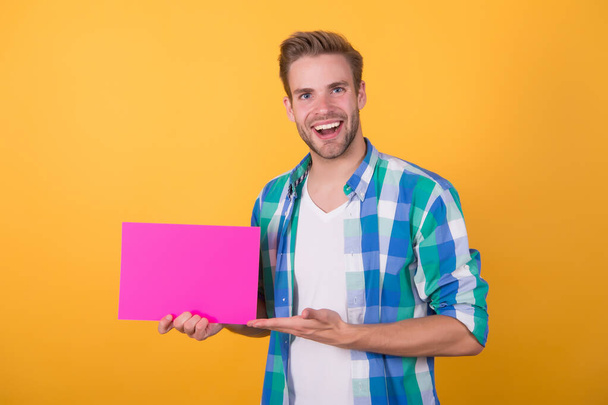 You need this product. Happy guy hold pink sheet and open hand. Presenting product. Product promotion. Marketing and sales. Product advertising, copy space - Foto, Bild