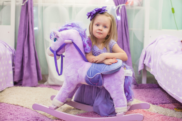 Adorable little girl with a toy horse at home - Foto, imagen