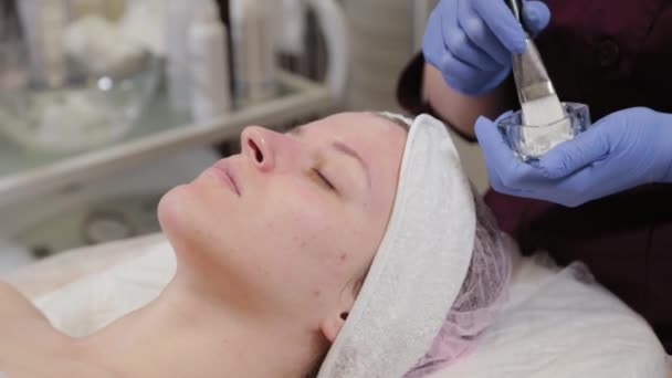 Professionelle Kosmetikerin trägt einer Frau eine Gesichtsmaske auf. - Filmmaterial, Video