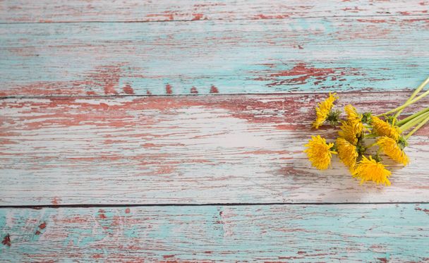 Świeże żółte kwiaty mniszka lekarskiego na drewnianym tle. Wygląda jak słońce w pokoju. - Zdjęcie, obraz