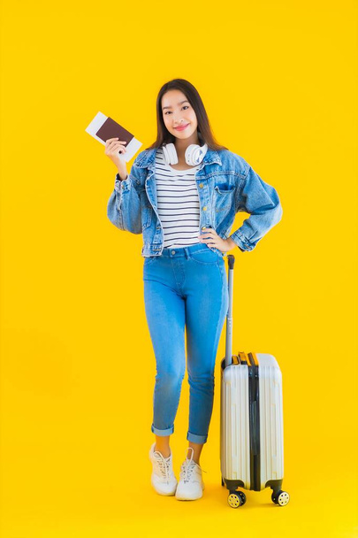 Portrait beautiful young asian woman travel and leisure with luggage bag and passport , boarding pass on yellow isolated background - Zdjęcie, obraz