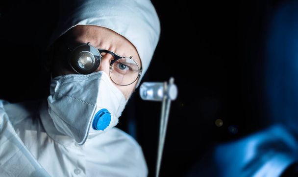 scientist doctor in uniform and glasses with a monocular magnifying glass microscope examines the substance of the virus in a capsule. laboratory tests. - Zdjęcie, obraz