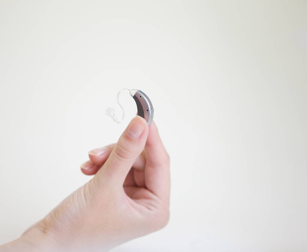 Very small hearing aid in a female hand - 写真・画像