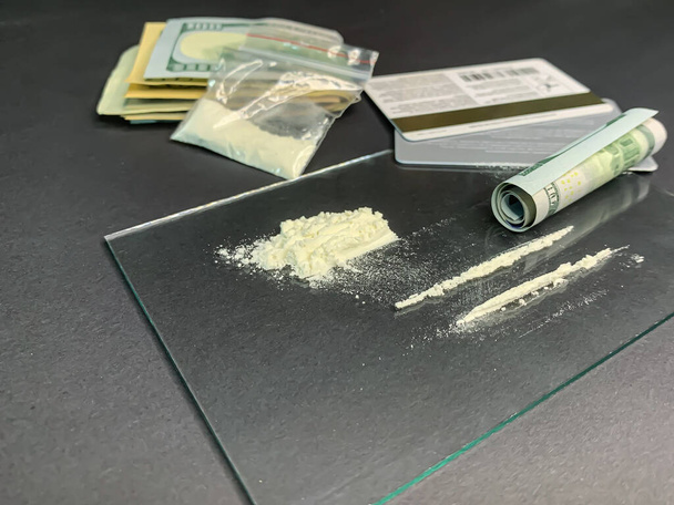 100 US-Dollar, zwei Reihen Kokain, Plastiktüten mit illegalen Drogen und Kreditkarten auf grauem Hintergrund. Drogensucht. Archivbild. - Foto, Bild
