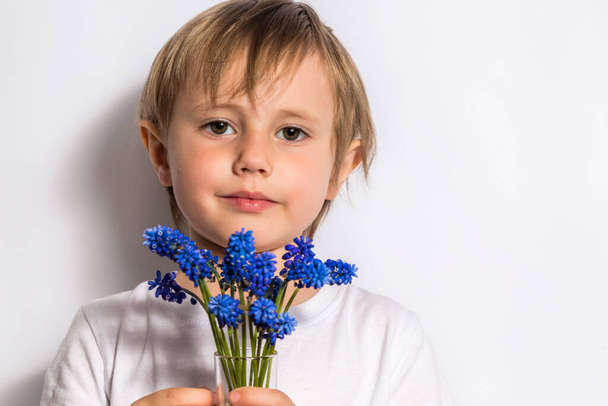 Ritratto del bel bambino tiene un mazzo di fiori blu per sua madre
. - Foto, immagini