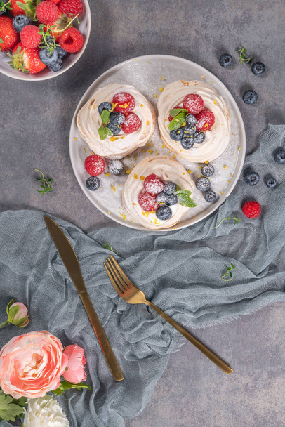 Mini pasteles de merengue pavlova con frambuesas frescas y arándanos con hojas de menta
. - Foto, Imagen