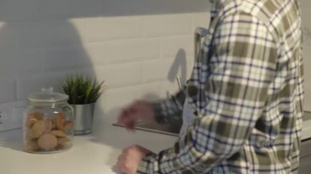 Asian man eating a cookie at home in the kitchen. - Materiał filmowy, wideo