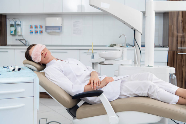 After hours in the dental clinic. A doctor is relaxing in her ch - Фото, зображення