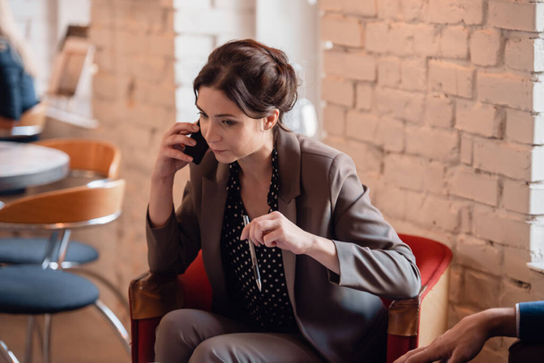 コーヒーを飲みながら電話で話しているビジネスマンの女性 - 写真・画像