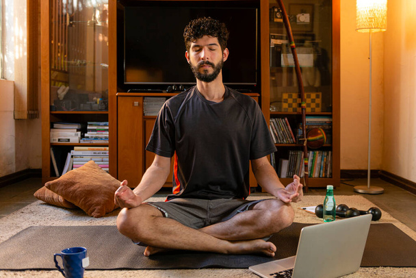 Человек в позе лотоса, практикующий йогу через онлайн видео классы
. - Фото, изображение