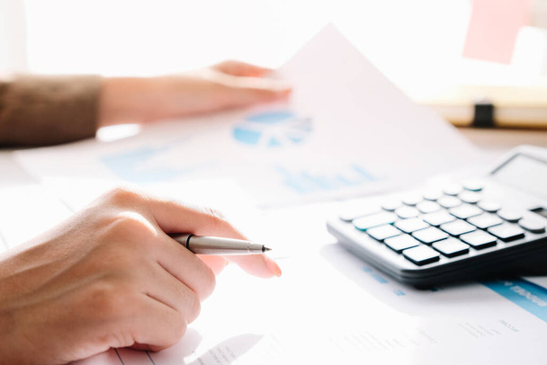 Close-up van zakenman of accountant hand holding pen werken op rekenmachine om zakelijke gegevens te berekenen, - Foto, afbeelding