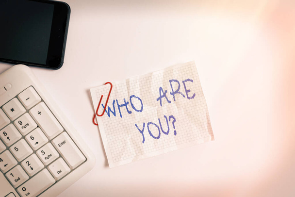 Χειρόγραφο κείμενο "Ποιος είσαι εσύ". Έννοια σημαίνει ρωτώντας για την ταυτότητα κάποιου ή μια ατομική πληροφορία Λευκό πληκτρολόγιο PC με άδειο χαρτί σημείωμα πάνω από το λευκό φόντο και το κινητό τηλέφωνο. - Φωτογραφία, εικόνα