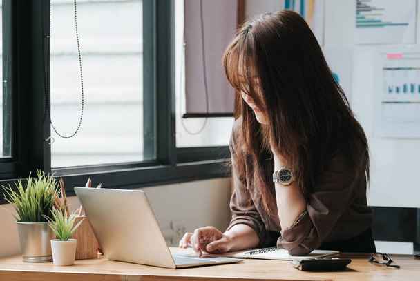 Femme d'affaires utilisant un ordinateur portable et une calculatrice pour faire des finances mathématiques sur un bureau en bois au bureau
 - Photo, image